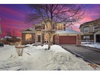 Two-story home with brick facade, snow-covered yard, and attached garage at 8631 Gladiola Cir, Arvada, CO 80005