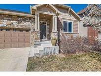 Charming home featuring a stone facade, covered front porch, and attached two-car garage at 5181 Delphinium Cir, Brighton, CO 80601