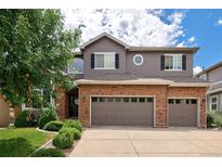 Two-story house with brick and siding, three-car garage, and landscaped lawn at 10682 W Indore Dr, Littleton, CO 80127