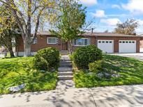 Charming brick ranch home featuring a two-car garage and landscaped front yard with mature trees in a suburban neighborhood at 12022 W Louisiana Ave, Lakewood, CO 80228