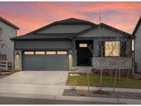 Charming single Gathering home with a two-car garage and stone accents at dusk at 24088 E Atlantic Pl, Aurora, CO 80018