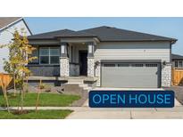 Ranch style home with gray siding, stone accents, and a two-car garage at 17305 E 91St Pl, Commerce City, CO 80022