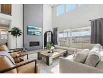 Bright living room with fireplace, large windows, and comfortable seating arrangement at 6361 Kenzie Cir, Castle Pines, CO 80108