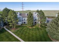Well maintained gray townhome featuring a lush lawn and mature trees at 7452 Singing Hills Dr, Boulder, CO 80301