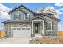 Charming two-story home with stone accents, blue siding and a two car garage at 15499 Kearney St, Brighton, CO 80602