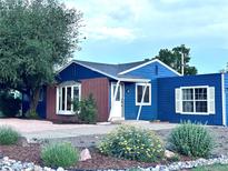 Charming home featuring blue siding, brick accents, mature landscaping, and a well-maintained front yard at 10130 W 20Th Ave, Lakewood, CO 80215