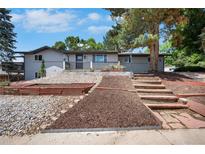 Charming exterior featuring a split level home, garden beds, landscaping, and a stairway leading to the front door at 9227 W 67Th Ave, Arvada, CO 80004