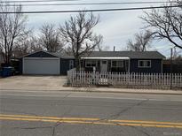 Charming single-story home with a white picket fence and a spacious two-car garage at 7060 E 60Th Ave, Commerce City, CO 80022