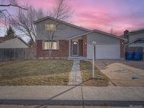 Brick and gray siding home with a two-car garage and landscaped yard at 13854 W 76Th Ave, Arvada, CO 80005