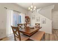 Bright dining room boasts modern light fixture, seating for six, and sliding glass doors for ample natural light at 23920 E 34Th Ave, Aurora, CO 80019