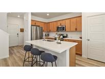 Modern kitchen featuring stainless steel appliances, breakfast bar with seating, and wood cabinets at 23920 E 34Th Ave, Aurora, CO 80019