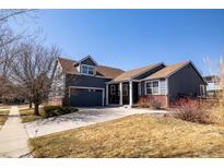 Charming two-story home with blue exterior, brown roof, manicured lawn, and attached garage at 275 Gold Maple St, Brighton, CO 80601