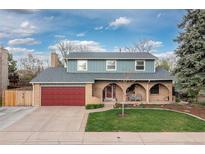 Charming two-story home with a well-manicured lawn, red garage door and inviting front porch at 6930 S Yukon Way, Littleton, CO 80128