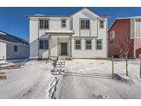 Charming two-story home featuring white siding, gray trim, and a welcoming front porch in a snowy setting at 2916 Oxley St, Strasburg, CO 80136