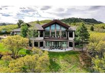 Stunning two-story home featuring a wall of windows, stone accents, and a spacious patio with outdoor seating at 580 Summer Mist Cir, Castle Rock, CO 80104