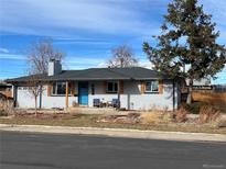 Charming single-story home featuring a blue front door, gray brick, and a well-maintained yard at 1941 Sherrelwood Cir, Denver, CO 80221