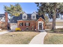 Charming brick home featuring dormer windows, a landscaped front yard and walkway leading to the front door at 700 Holly St, Denver, CO 80220