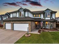 Charming two-story home featuring a three-car garage, manicured lawn, and classic brick and siding accents at 5426 S Jasper Way, Centennial, CO 80015
