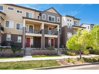 Townhome with brick and siding, featuring small, private balconies and red front doors, set in a community with green landscaping at 630 E Hinsdale Ave, Littleton, CO 80122