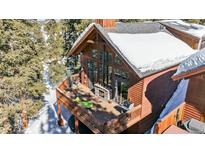 Stunning exterior showcasing an expansive deck with a stone fireplace perfect for outdoor gatherings at 960 Whispering Pines Ln, Breckenridge, CO 80424