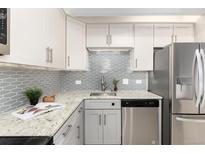 Updated kitchen features stainless steel appliances, grey cabinetry, granite counters, and modern backsplash at 555 E 10Th Ave # 206, Denver, CO 80203