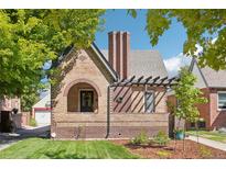 Charming brick home featuring a unique archway, pergola, manicured lawn and a classic chimney design at 1552 Hudson St, Denver, CO 80220