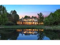 A serene two-story home at dusk, reflecting beautifully in a tranquil pond at 13 Buell Mansion Pkwy, Englewood, CO 80113