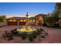 Stunning home exterior featuring a circular driveway and illuminated tiered fountain at dusk at 11541 Warrington Ct, Parker, CO 80138