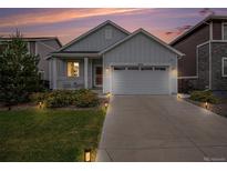 Charming home featuring a landscaped front yard, two-car garage, and a welcoming covered porch at twilight at 26787 E Maple Ave, Aurora, CO 80018