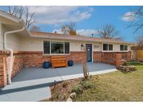 Charming home featuring a brick facade, blue door, and inviting front porch at 11542 W 67Th Way, Arvada, CO 80004