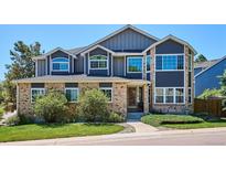 Two-story home showcasing a brick and navy blue exterior with a well-manicured lawn and mature shrubs at 7804 Silverweed Way, Lone Tree, CO 80124