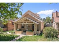 Charming front exterior featuring a covered porch with a well-manicured lawn and a brick facade at 1121 S Ogden St, Denver, CO 80210