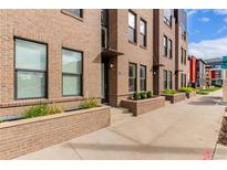 Modern brick townhome featuring large windows, a landscaped entrance, and a clean, urban design at 2436 Welton St, Denver, CO 80205