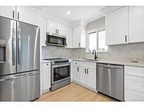 Modern kitchen with stainless steel appliances, white cabinets, and a bright window over the sink at 3657 Krameria St, Denver, CO 80207