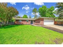 Charming single-story brick home with a well-manicured lawn and mature trees under a blue sky at 11267 W Colorado Pl, Denver, CO 80232