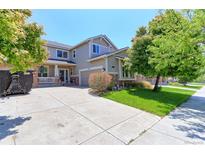 Two-story home featuring a manicured lawn, covered porch, and an attached two-car garage at 9994 Quintero St, Commerce City, CO 80022