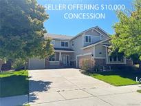 Charming two-story home with attached garage, landscaped yard, and inviting front porch with stone accents at 9994 Quintero St, Commerce City, CO 80022