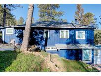Blue home featuring lots of windows and natural rock formations on the property at 4642 Plettner Ln, Evergreen, CO 80439
