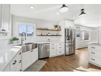 Bright kitchen features stainless steel appliances, farmhouse sink, open shelving, and gleaming hardwood floors at 767 Ellis St, Golden, CO 80401