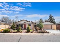 Charming single-story home featuring a manicured front yard and a welcoming red front door at 10874 Pearl Ct, Northglenn, CO 80233