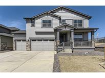 Two-story home with gray siding, stone accents, three-car garage, covered porch, and well-manicured lawn at 2968 S Poppy St, Morrison, CO 80465