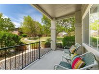 Relaxing balcony with chairs, table, and vibrant pillows overlooking the well-maintained community landscape at 2239 Calais Dr # 11F, Longmont, CO 80504
