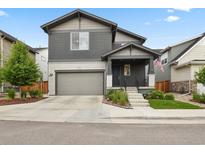 Two-story home with gray siding, brick accents, a well-kept lawn, and an attached two-car garage at 11151 W 53Rd Dr, Wheat Ridge, CO 80033