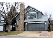 Charming two-story home features gray siding, brick chimney, and a two-car garage at 4243 Flanders St, Denver, CO 80249
