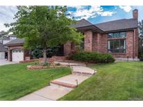 Charming brick home featuring a well-manicured lawn, mature trees, and a welcoming walkway to the front entrance at 8047 S Fairfax Ct, Centennial, CO 80122