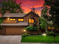 Charming two-story home with a well-manicured lawn and a two-car garage, all under a beautiful sunset at 5860 W Atlantic Dr, Lakewood, CO 80227