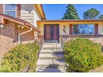 Inviting home entrance with double doors, brick accents, and landscaped bushes, offering a warm welcome at 3792 S Fenton Way, Denver, CO 80235