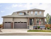 Charming two-story home featuring a welcoming front porch, three-car garage and manicured lawn at 15977 Red Bud Dr, Parker, CO 80134