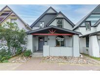 Charming two-story home featuring a gray exterior, lovely porch, and a well-manicured front yard at 2211 W 33Rd Ave, Denver, CO 80211