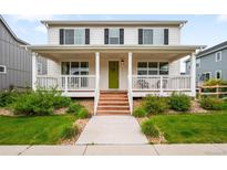 Charming home featuring a inviting covered porch, green door, white siding and manicured landscaping at 12845 Park Creek Way Way, Firestone, CO 80504